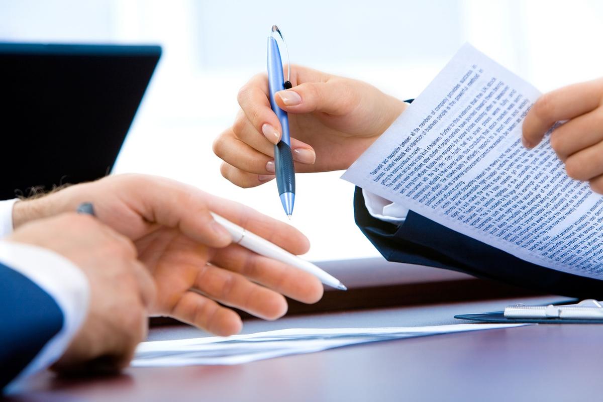 Deux personnes à un bureau signent des documents, ordinateur portable visible, contexte professionnel Deux personnes à un bureau signent des documents, ordinateur portable visible, contexte professionnel
