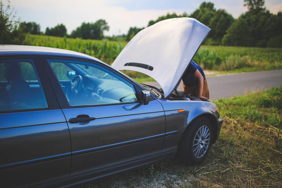 Une voiture avec le capot levé, un homme regarde le moteur Une voiture avec le capot levé, un homme regarde le moteur
