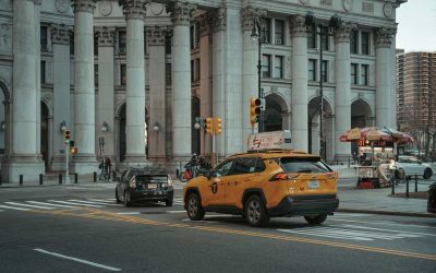 Taxi jaune et voiture noire devant un édifice monumental avec colonnes