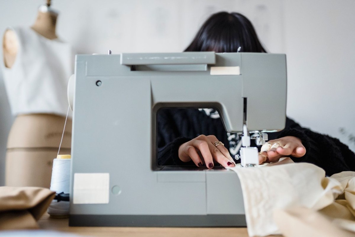 Femme utilisant une machine à coudre sur du tissu, mannequin à gauche