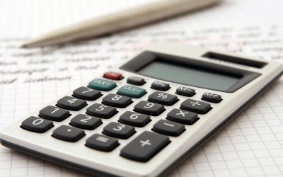 Calculatrice et stylo posés sur des documents comptables manuscrits