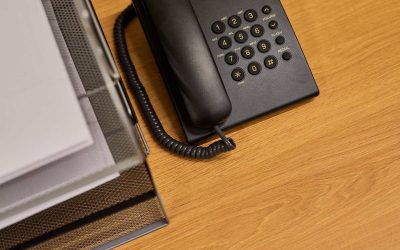 Un téléphone fixe posé sur un bureau en bois à côté d'un classeur