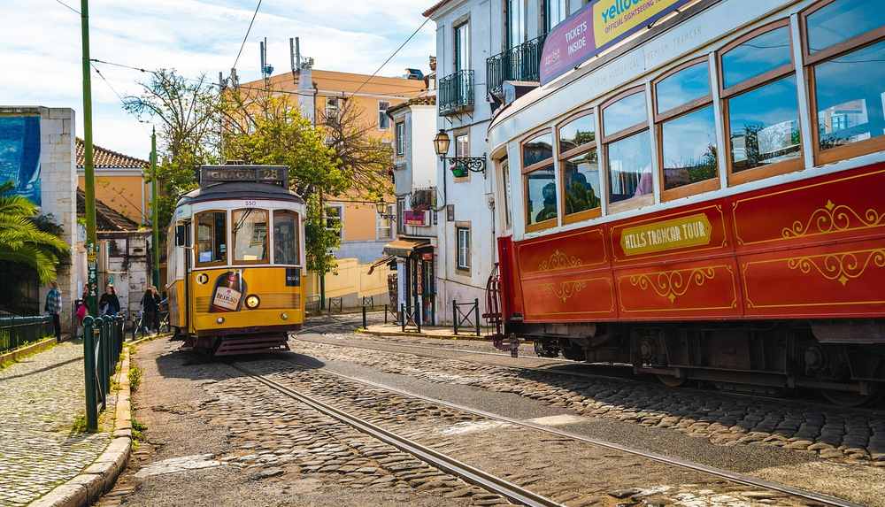 Deux tramways vintage, un jaune et un rouge, sur rails pavés