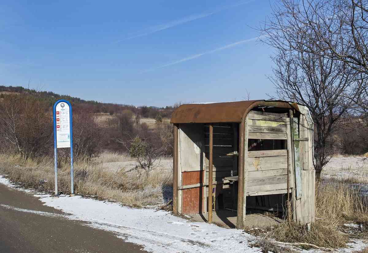Abri de bus délabré à côté d'une route enneigée sous un ciel clair
